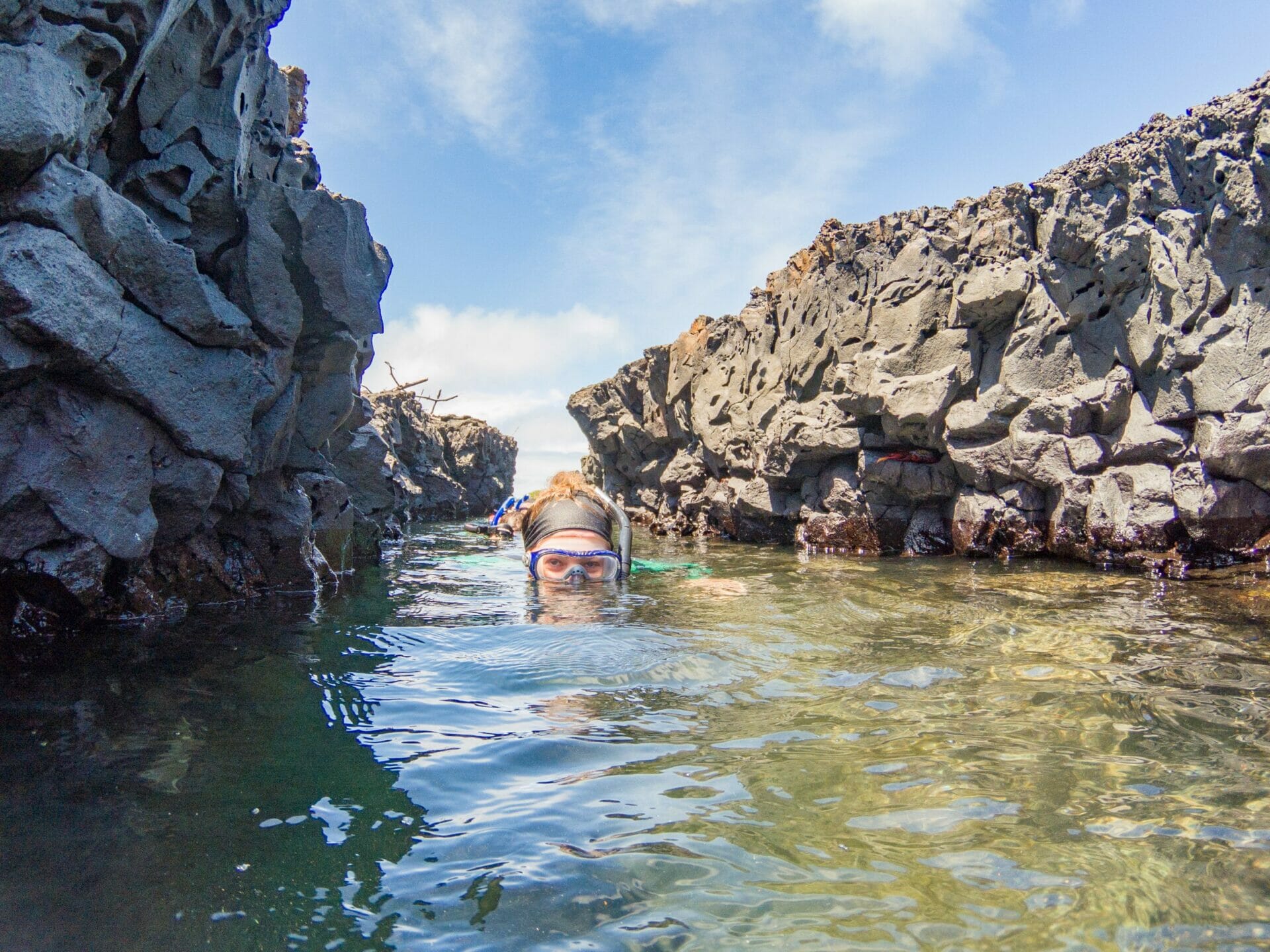 Woman snorkelling through lava tunnel at Las Tintoreras